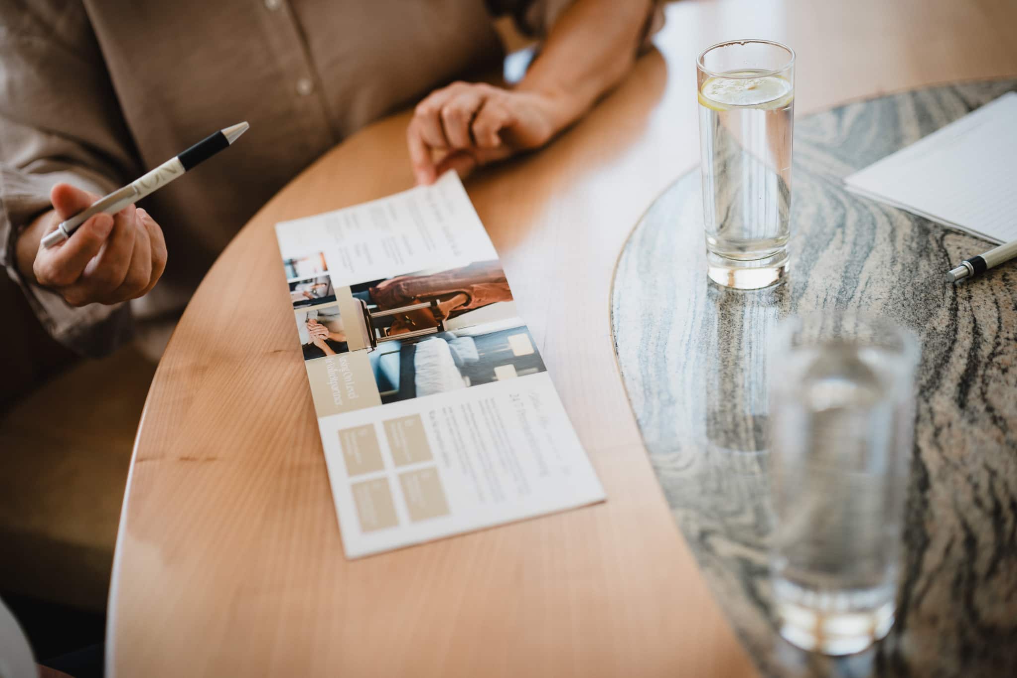 Pflegeberaterin erläutert Informationsmaterial zur 24-Stunden-Pflege bei einem persönlichen Beratungsgespräch.