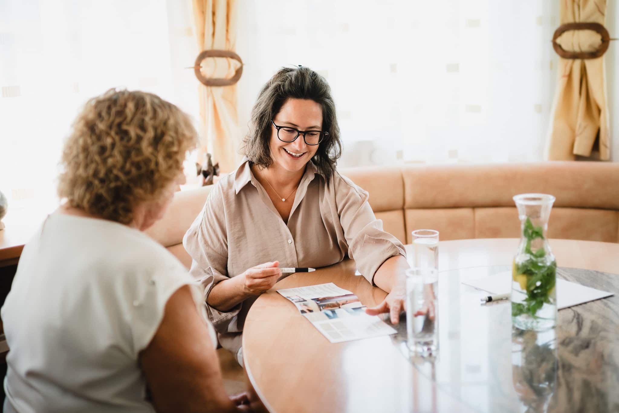 Manuela Sternig erklärt einer älteren Dame in ruhiger Atmosphäre Unterstützungsangebote der 24-Stunden-Pflege.
