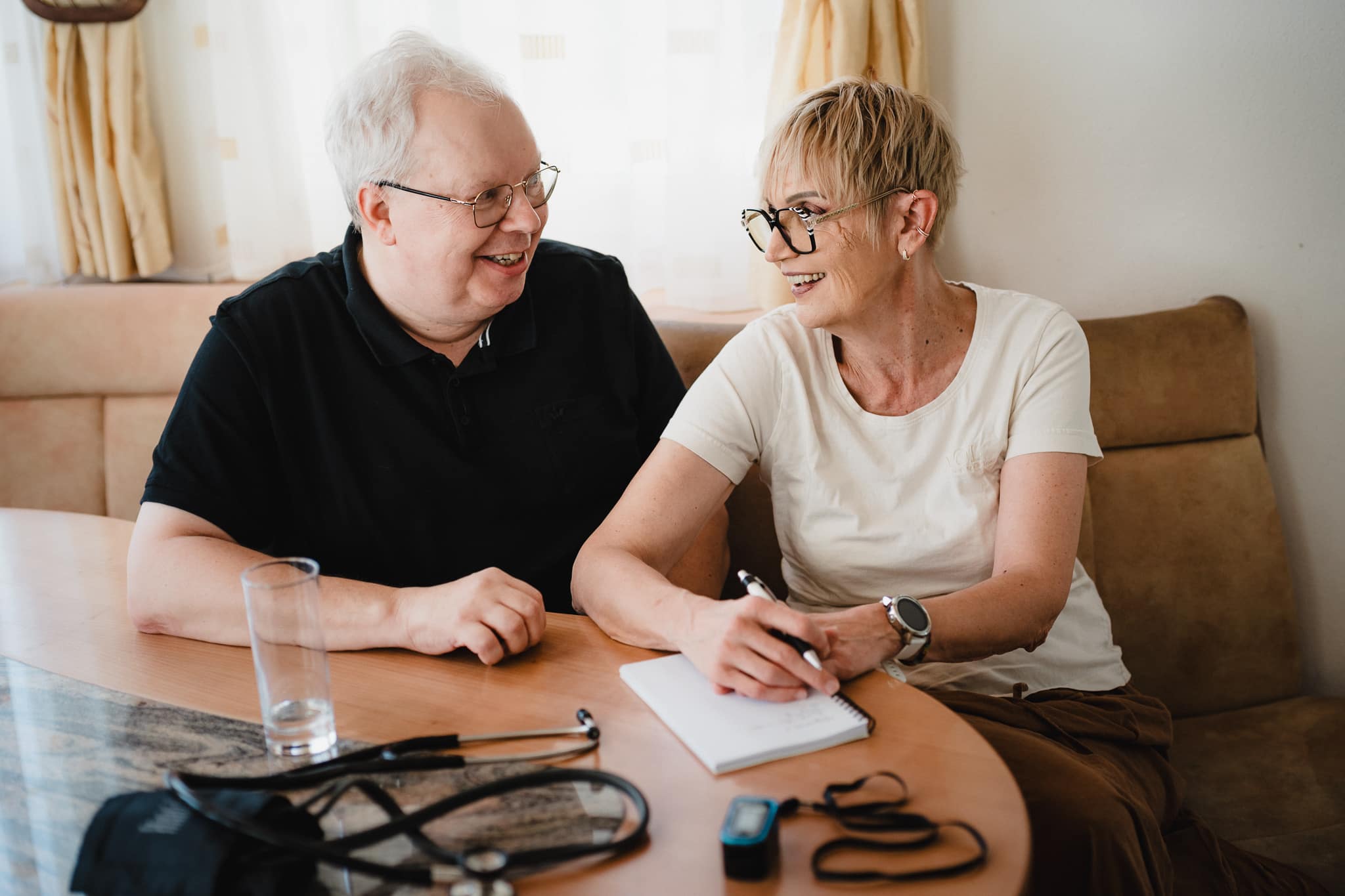 Pflegekraft im persönlichen Gespräch mit Klient bei privater Pflege zu Hause.